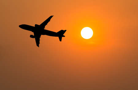 Silhouette of big airplane on beautiful orange sunset background, fast aerial transport, traveling and voyage conceptの写真素材