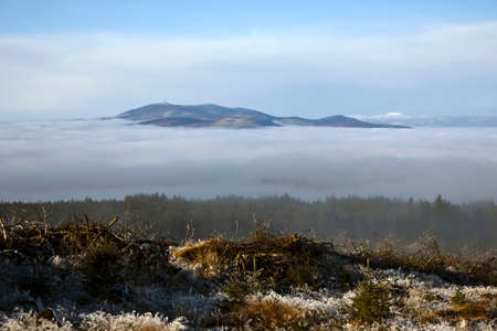 Picturesque image of Knockmealdown Mountains protruding from the fog covering Araglin Valley in...
