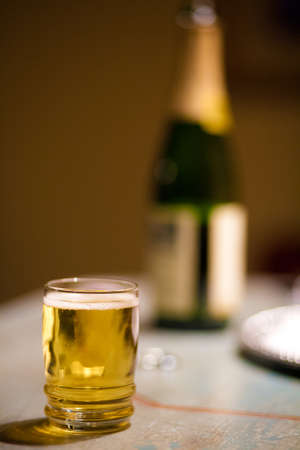 A detail shot of a glass of apple cider with the bottle in the backgroundの写真素材