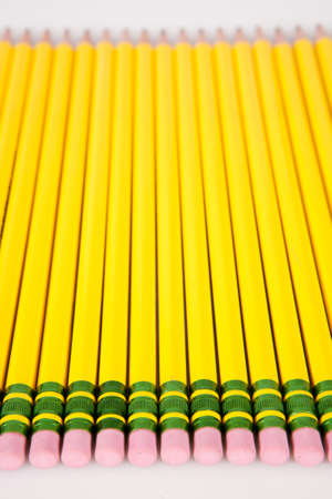 A group of yellow, #2 pencil erasers laid out in a row on white.の写真素材