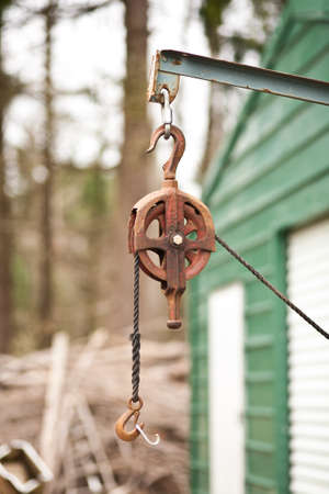 A rusty metal pulley with a rope and hook.の写真素材