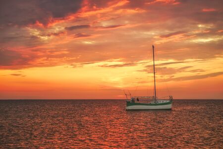 Sailboat in the sea against sunset skyの写真素材