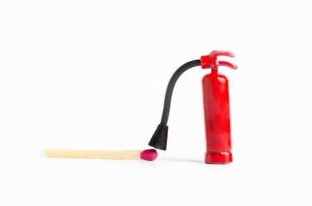 Very small fire extinguisher close to a fresh unburned match against a white background, macro shot