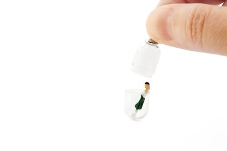 Closing a miniature model of a woman inside a plastic capsule for infection prevention during quarantine. Covid-19 social distancing conceptの写真素材