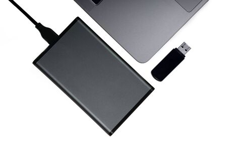 Portable hard disk connected to a laptop and a black flash drive isolated on white, flat lay. Data...