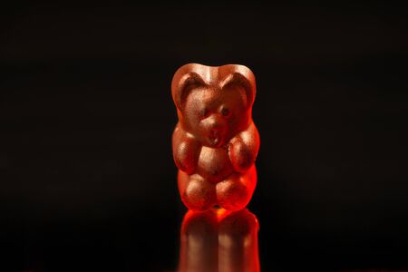 Close-up of a dark red gummy bear on a black background