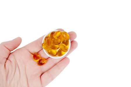 Female hand holds fish oil capsules isolated on white.