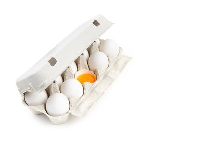 White paper carton with chicken eggs. One half of an eggshell contains a yolk. Isolated on white, top-side view.の写真素材