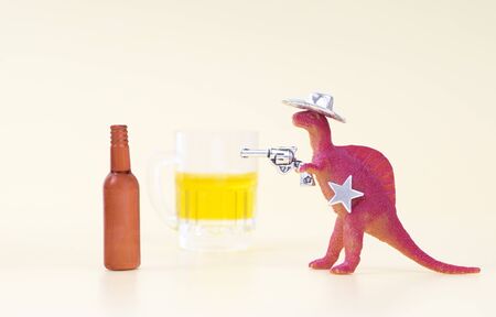 Toy dinosaur wearing a cowboy hat, holding a revolver in his arm and having a sheriff star shoots an...