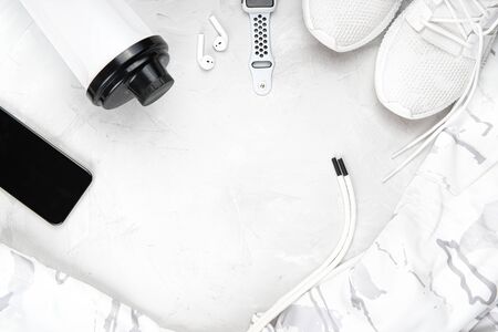 Flat lay of fitness accessories: sneakers, training hoodie, shaker, phone, truly wireless earphones and sport watches on a grayの写真素材