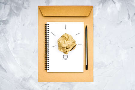 Light bulb symbol made of a crumpled paper ball and a sketch on a spiral notebook. Creative process concept.の写真素材