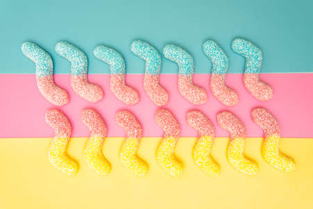 Two rows of multicolored sugar coated gummy worms on a vivid backgroundの写真素材