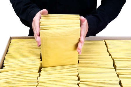 Man in black uniform packing yellow padded bubble envelopes in a large cardboard box
