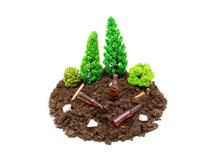 Miniature toy forest composition with beer bottles, paper rubbish and matches lying around.The concept of keeping forests and parks clean.の写真素材