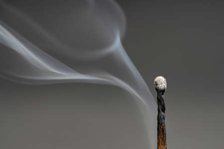 Close-up of the smoke coming from an extinguished match on a grey backgroundの写真素材