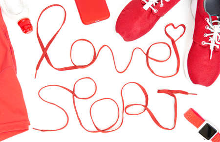 Flat lay of running accessories including a lettering LOVE SPORT made of athletic shoelaces, shoes, smartphone, smartwatch, top and a water bottle isolated on white background. Active lifestyle concept.の写真素材