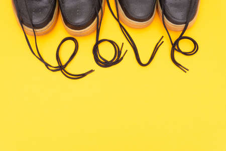 Crop view of two pairs of matching leather sneakers with the word LOVE arranged of the shoelaces on...