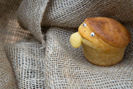 Side view of a funny character made of a homemade muffin on a burlap cloth.の写真素材