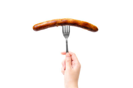 Close-up of female hand holding a fork with a grilled german sausage isolated on white background.の写真素材