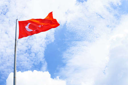 Low angle view of the flag of Turkey waving against blue sky on a sunny dayの写真素材