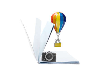 Blank passport with a camera figurine and a hovering air balloon pendant isolated on white. Romantic...