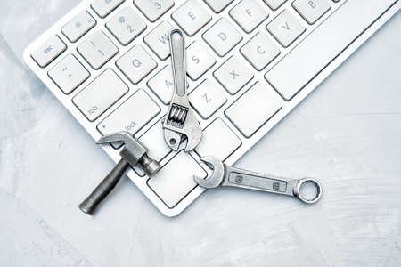 Keyboard and a miniature hand tools set on a concrete table. Hardware repair service concept.の写真素材
