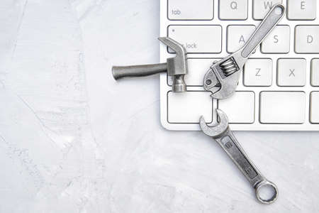 Island style keyboard and a miniature hand tools set on a concrete table. Hardware repair service concept.の写真素材
