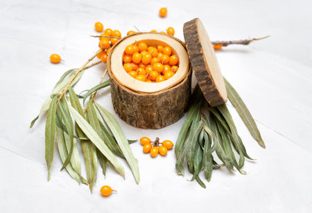 Close-up of a handmade wooden bowl with ripe sea buckthorn berries on a neutral background