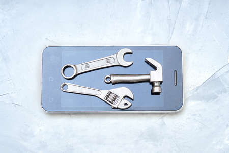 Cell phone with a set of hand tools on a concrete table. Choosing a proper mobile repair tools kit.の写真素材