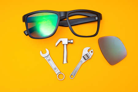 Broken sunglasses with a set of hand tools on a yellow background. Repair service concept.の写真素材
