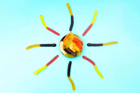 Sun shape made of multicolored gummy worms on a blue backgroundの写真素材