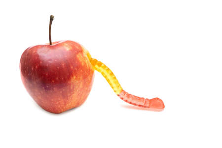 Gummy worm coming out of a fresh red apple isolated on whiteの写真素材