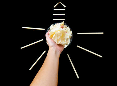 Light bulb symbol made from crumpled paper balls on a black background. Idea development concept.