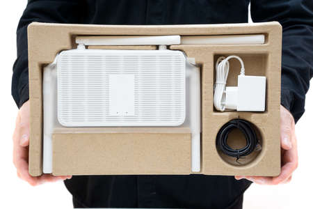 Man in black uniform showing a dual band WiFi 6 router with accessories in a retail box.の写真素材