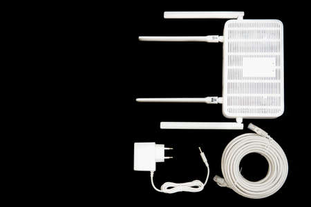 Top view of a dual band WiFi 6 router with a power supply adapter and a roll of cable isolated on black.の写真素材
