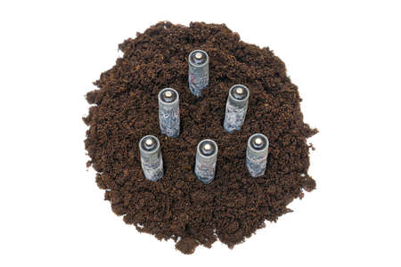 Corroded used batteries standing in a pile of soil isolated on white background. Nature...