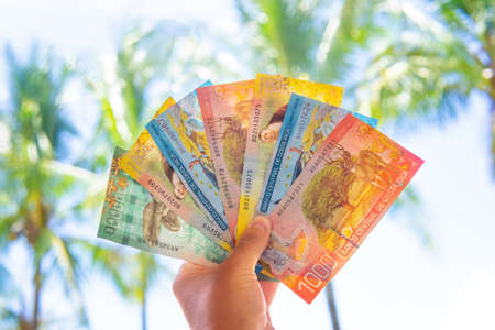 Hand holding Costa Rican banknotes against a tropical backgroundの写真素材