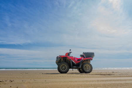 Low angle view of a red all-terrain quad bike standing on the sandy beach of Costa Rica at noonの写真素材