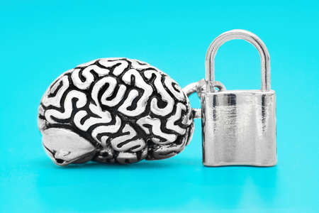 Anatomical copy of a human brain with a locked padlock isolated on blue background. The concept of unlocking the mind power.の写真素材