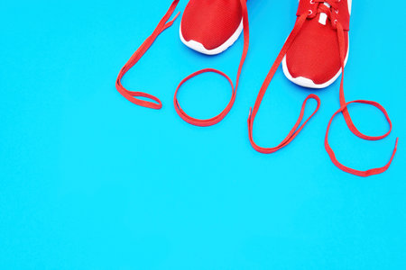 Word LOVE made from the laces of the pair of red athletic shoes isolated on a blue background. Love for running.の写真素材