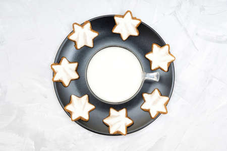 Top view of a plate of authentic german cinnamon star cookies and a glass of milk left out for Santa on a Christmas eve.の写真素材