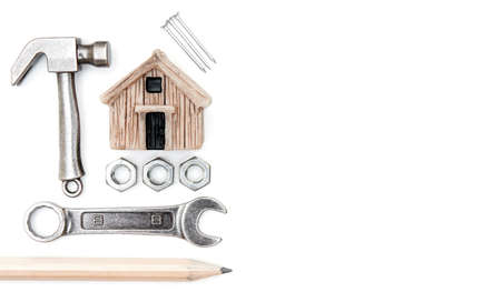 Miniature toy house, small hammer, wrench, nuts, nails and a pencil isolated on a white background. Home improvement and repair concept.の写真素材