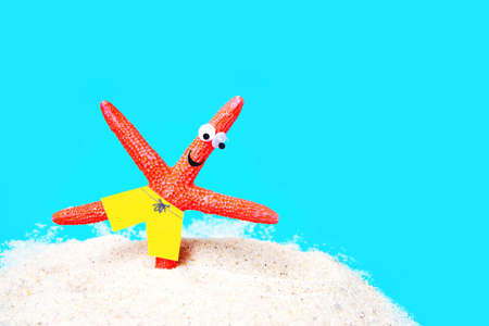 Funny starfish character having a yoga session on a sandy beach. Active summer vacation concept.の写真素材