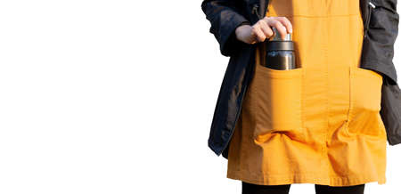 Crop view of a female model wearing an orange dress and having a thermal flask in a pocket.