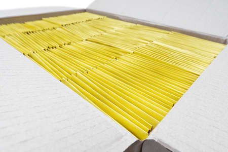 Open cardboard box packed with yellow padded envelopes, selective focus
