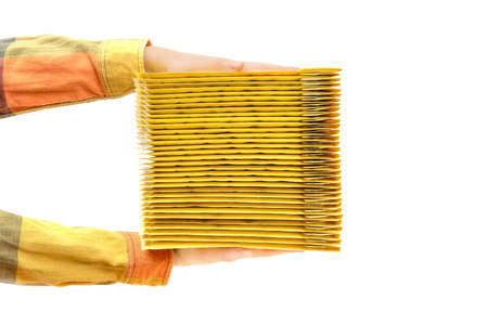 Hands holding a stack of yellow shipping envelopes. Side view, isolated on white