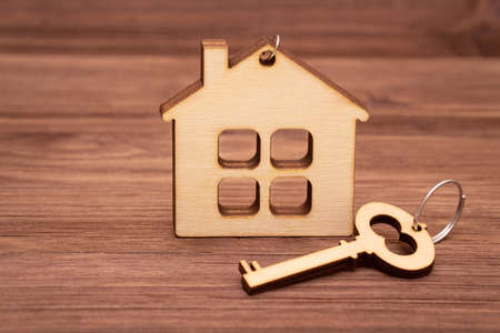 Flat house shape and a house key made of wood. Buying a prefabricated home.の写真素材