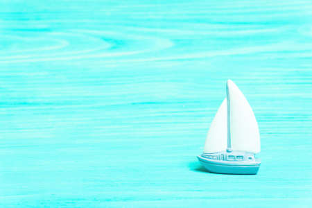 Miniature toy yacht on a turquoise wooden table background imitating water.の写真素材