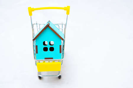House model in a shopping cart on gray. Real estate sale concept.の写真素材