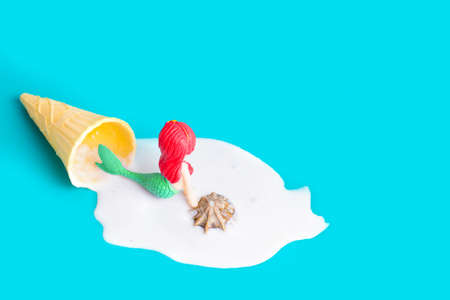 Mermaid figurine swimming in melted waffle cone ice cream on blue.の写真素材